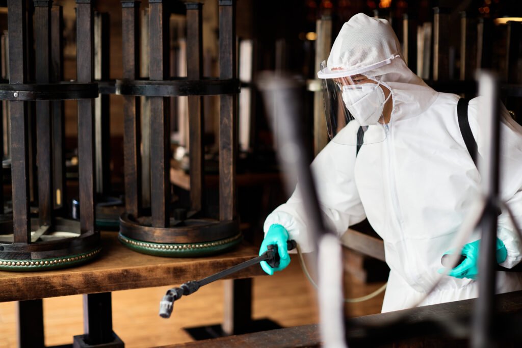 Worker in protective suit disinfecting a room